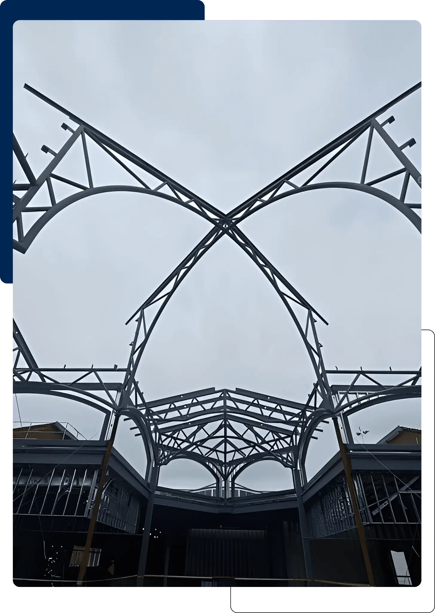 Steel framework of a modern roof structure against a cloudy sky.