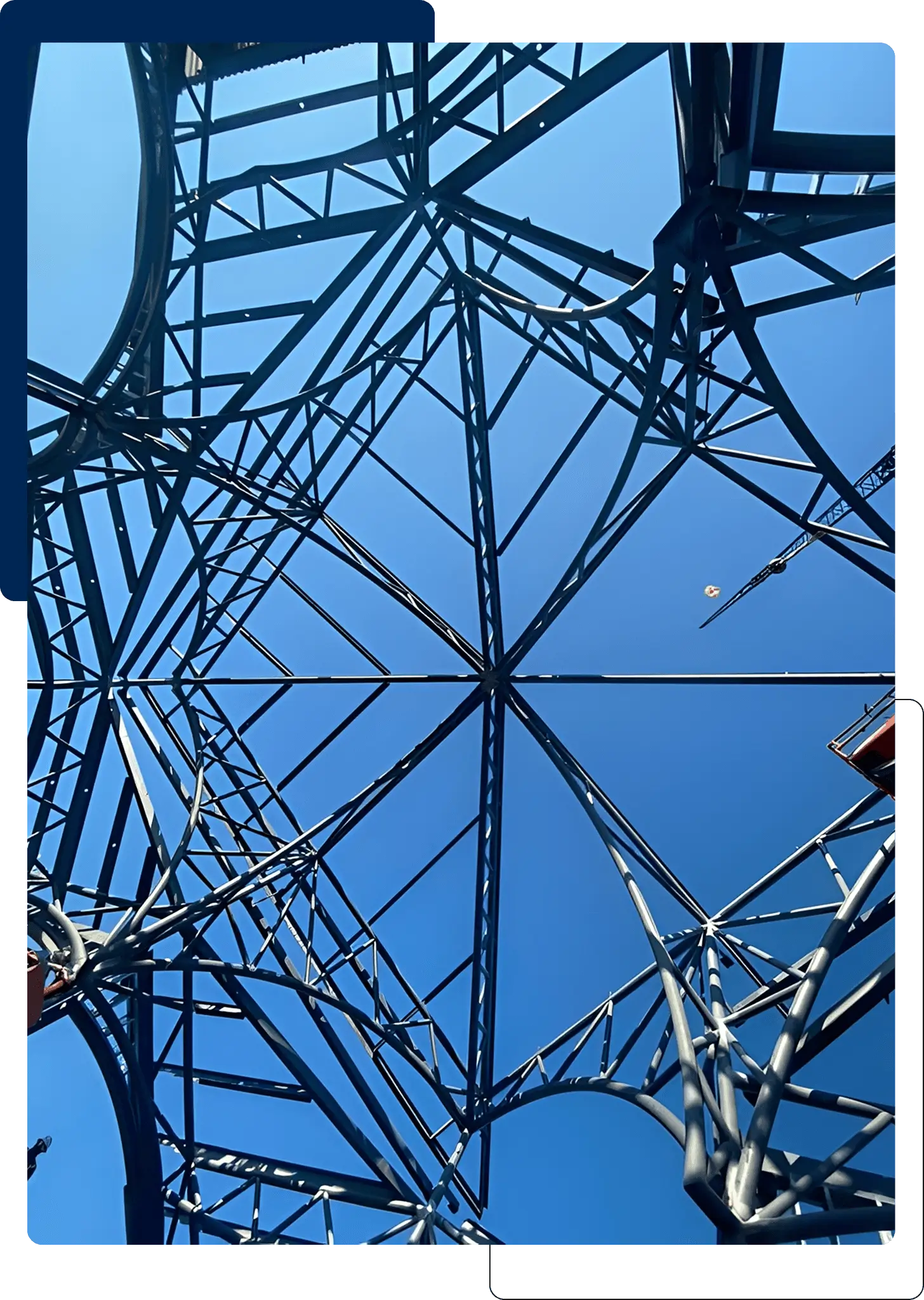 View looking up inside a metal electrical tower against a blue sky.